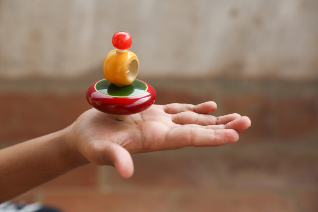 boy holding wooden spinning top toy