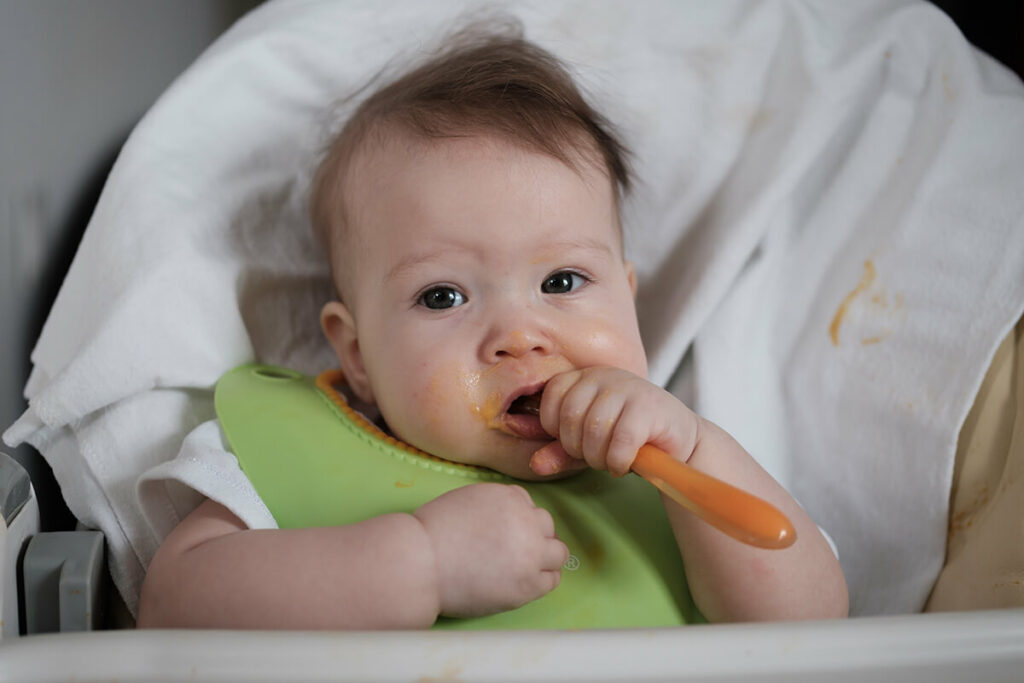 baby eating solid food with a spoon baby's first foods