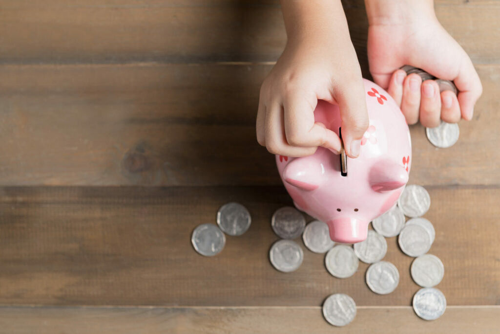 preschooler putting money in piggy bank