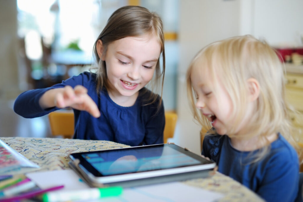 two preschoolers playing with a tablet